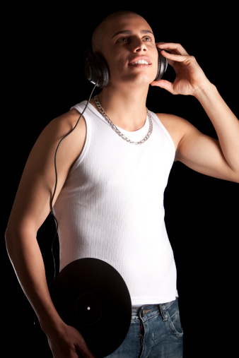 A good looking, muscular built, man on a black background with earphones.