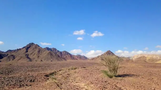 Desert landscape - Aerial image of mountains and dry land with blue cloudy sky in the background.