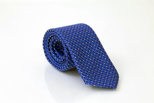 Rolled blue men's tie isolated on white glassy background, closeup