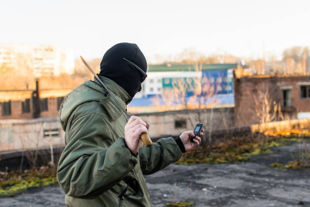 criminale con un grosso coltello guarda nel telefono - thief crime gun hostage foto e immagini stock