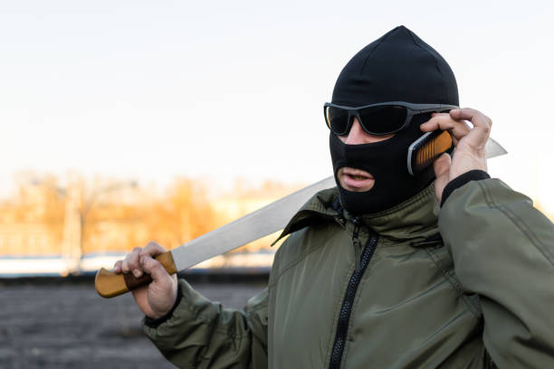 il bandito in occhiali e una maschera al telefono - thief crime gun hostage foto e immagini stock