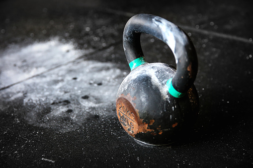 Close up kettlebell on black background, with scattered chalks on the floor