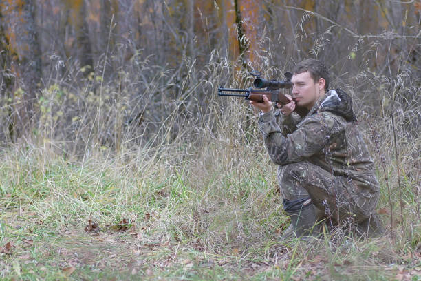 istock Man in camouflage and with guns in a forest belt on a spring hunt 1085213832