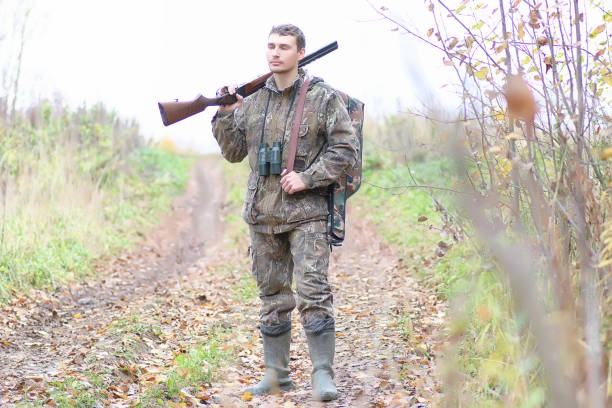 istock Man in camouflage and with guns in a forest belt on a spring hunt 1085213910