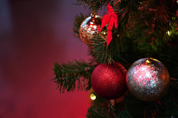 istock Christmas tree decorated with baubles and other traditional ornamnets in beautiful red light with copy space 1085218498