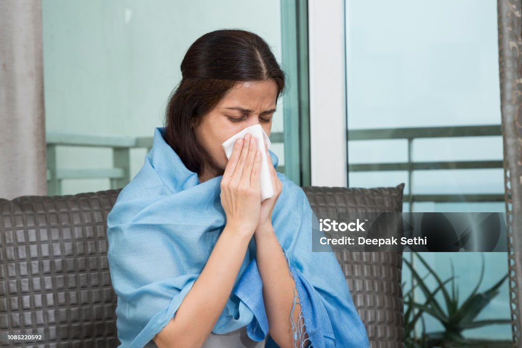 Sick woman blowing her nose - Stock image Women, One Woman Only, People, Sofa, Only Women India Stock Photo