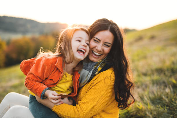 ein porträt der jungen mutter mit einer kleinen tochter im herbst natur bei sonnenuntergang. - laughing children stock-fotos und bilder