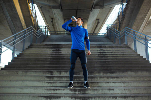 sportowiec pijący wodę i stojący na schodach - drinking men water bottle zdjęcia i obrazy z banku zdjęć