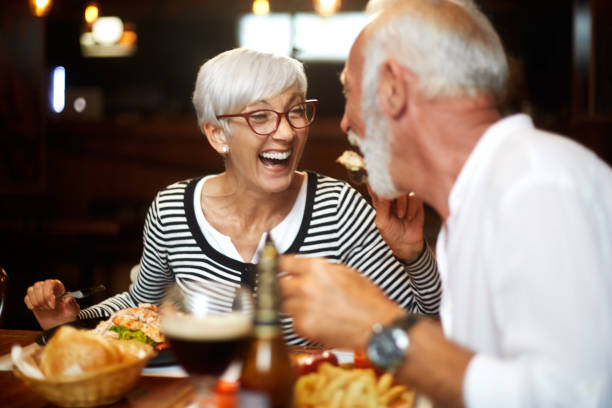 istock Elderly woman laughing while feeding her partner in a restaurant 1085234322