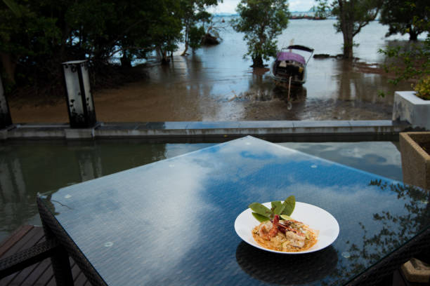 Shrimp with Pomelo lemon cashew nut, Fusion food stylish arrange on glass table along ocean mangrove tree Island, empty copy space for text logo