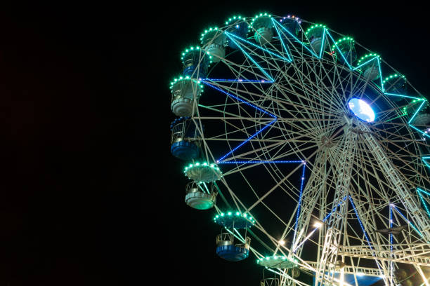 istock Colourful striped light illuminated spinning ferris wheel in motion moving at night. 1085245852