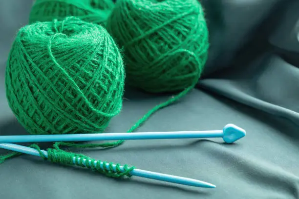 Green woolen threads and knitting accessories. Copy space