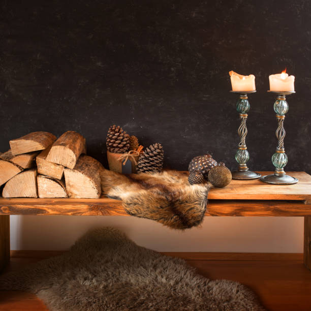 Christmas decoration with candles, bells  and  pine cones, before fiire burning in fireplace.