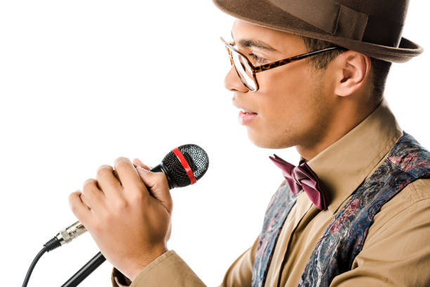 istock side view of handsome mixed race man in hat singing in microphone isolated on white 1085260052