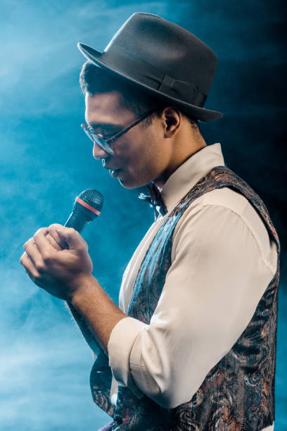 istock side view of male singer performing with microphone on stage with smoke and dramatic lighting 1085268326