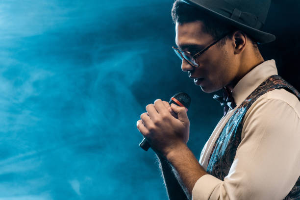 istock side view of handsome stylish man singing in microphone on stage with smoke and dramatic lighting 1085268334