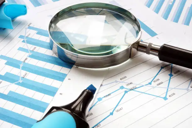 Photo of Magnifying glass and financial documents. Audit and accounting.