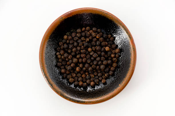 istock black pepper in a dish on white background 1085301488