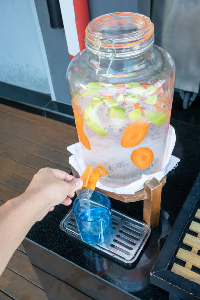 istock Woman hands pulling down the lever of water dispenser with fruit infused water. Refreshment concept 1085317694