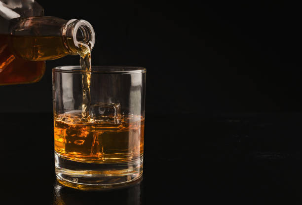 verter el whisky de la botella en vaso con hielo - whisky glass alcohol drink fotografías e imágenes de stock