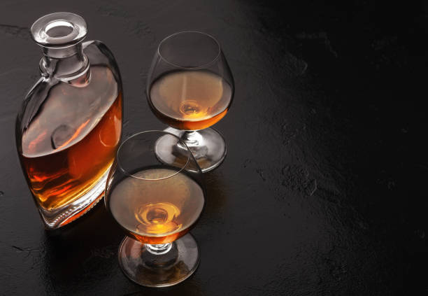 two glasses of brandy or cognac and bottle on black - hard liqueur imagens e fotografias de stock