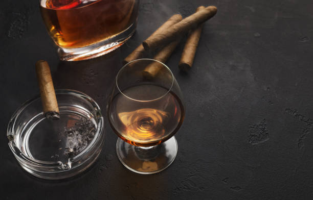 two glasses with cognac, bottle and cigars - cigar whisky bar cognac imagens e fotografias de stock