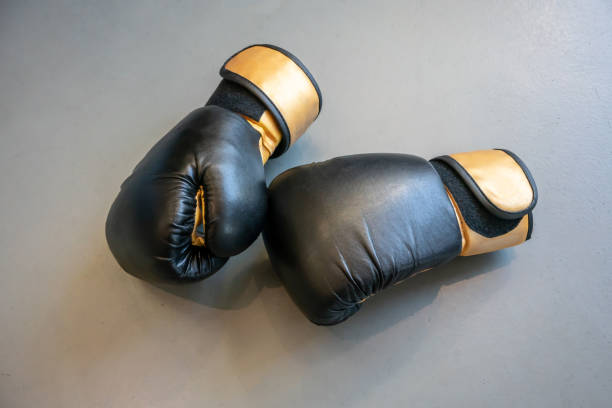 istock Old black and yellow boxing gloves on grey concrete background. - Image 1085324416