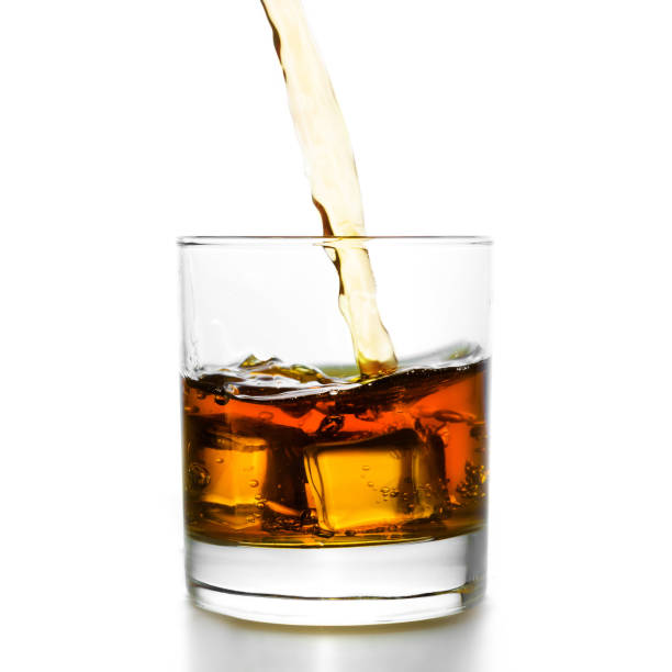 Golden whiskey pouring into lowball
