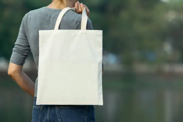 Photo of woman carry bag on nature background in save earth concept or say no plastic bag.