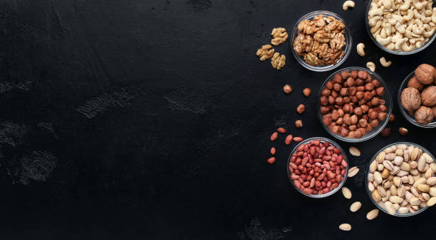 istock Various nuts in glass bowls on black background 1085328926