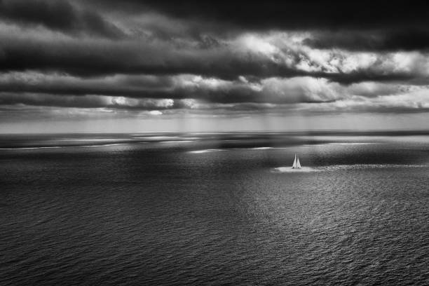 Sea scape with cloudy atmosphere and sailing boat and sun rays