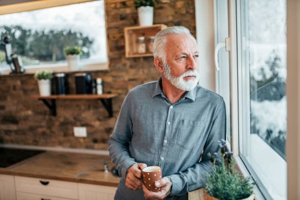 istock Senior man drinking coffee and looking through window, at home. 1085333374