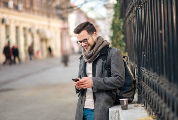 istock Trendy young man using mobile phone at city street. 1085334228