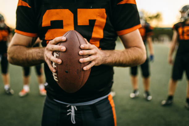 american football player holding ball - football player american football sports team teamwork imagens e fotografias de stock