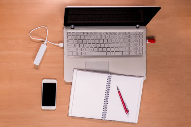 istock New technology on the desk: open laptop with charging power bank and memory stick connected, mobile phone and open notebook with red pen 1085342418