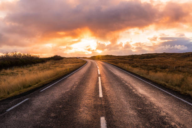 majestuosa puesta de sol naranja sobre una carretera en islandia - highway asphalt road empty fotografías e imágenes de stock