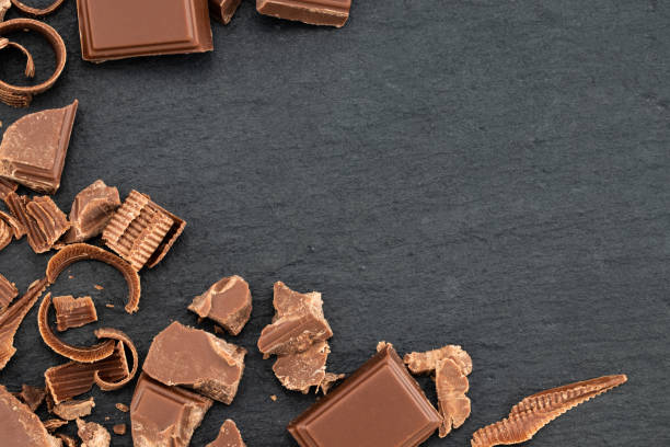istock Broken chocolate pieces and chocolate shavings on a dark background. Top view with copyspace for your text 1085346656