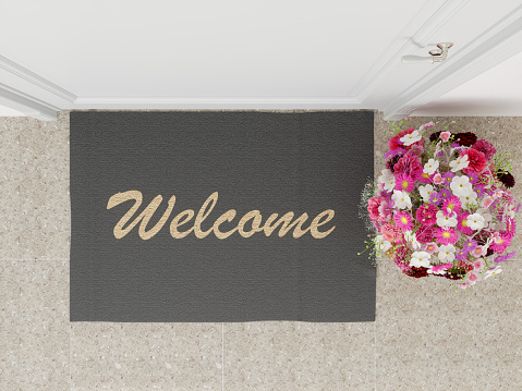 Welcome mat with flower at the front door overhead top view
