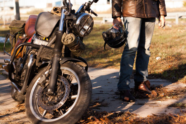 istock Man and old custom cafe-racer Motorcycle on forest  at sunset 1085351426