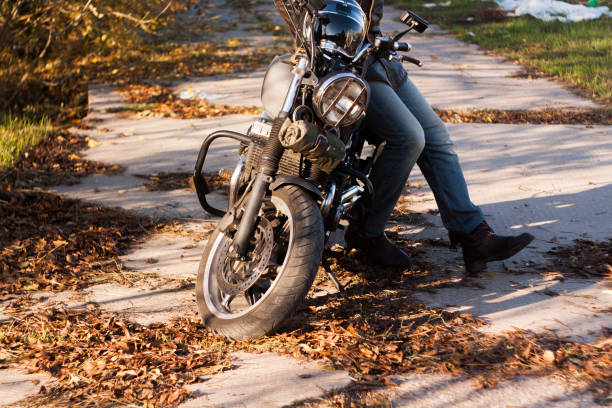 istock Man and old custom cafe-racer Motorcycle on forest  at sunset 1085352474