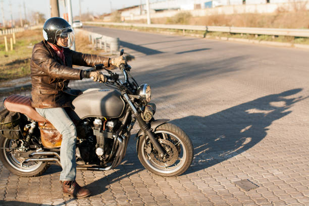 istock Man and old custom cafe-racer Motorcycle on forest  at sunset 1085352588