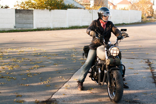 istock Man and old custom cafe-racer Motorcycle on forest  at sunset 1085352628