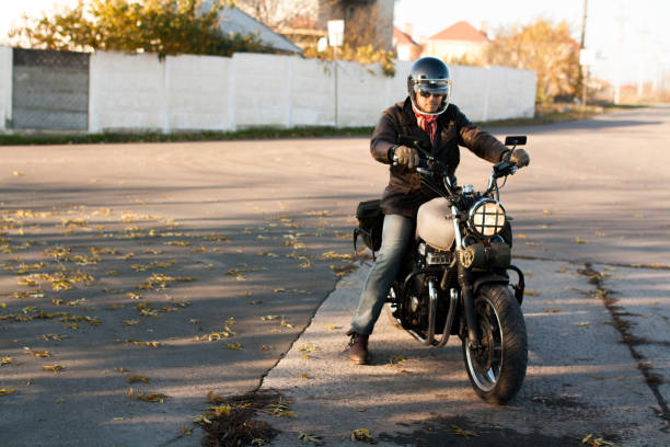 istock Man and old custom cafe-racer Motorcycle on forest  at sunset 1085352632