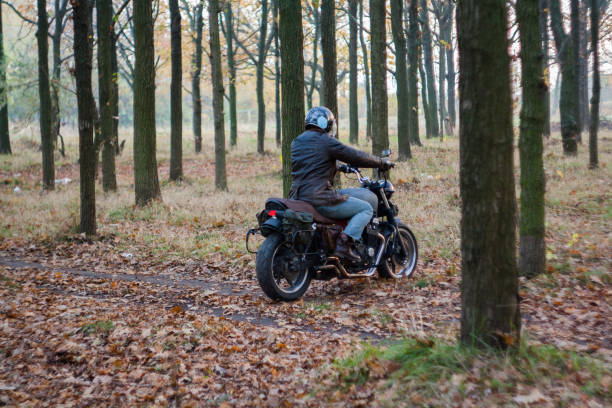 istock Man and old custom cafe-racer Motorcycle on forest  at sunset 1085352940