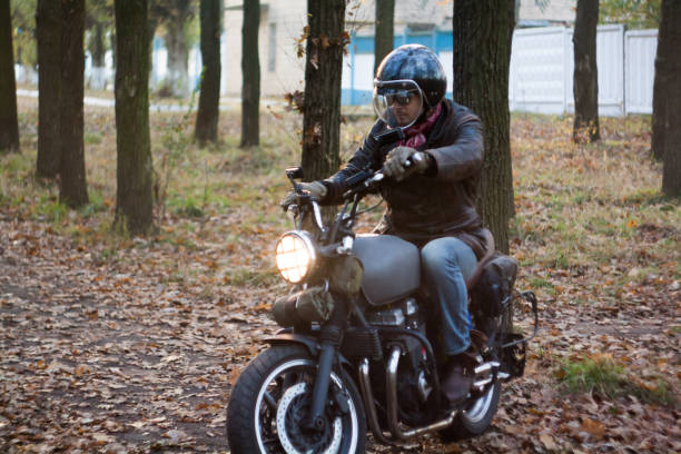 istock Man and old custom cafe-racer Motorcycle on forest  at sunset 1085352992