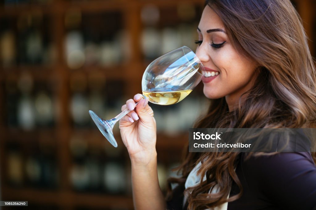 Portrait of female sommelier smelling wine before tasting it at wine cellar Portrait of beautiful woman tasting wine a wine cellar Wine Stock Photo
