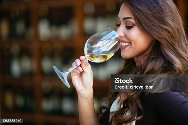 Portrait Of Female Sommelier Smelling Wine Before Tasting It At Wine Cellar Stock Photo - Download Image Now