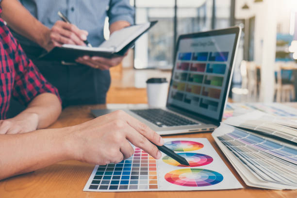 istock Teamwork of young creative designers working on project together and choose color swatch samples for selection coloring on digital graphic tablet at workspace 1085370986