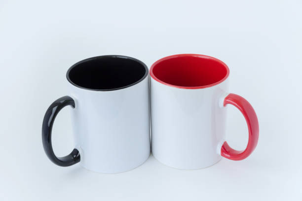 istock Two white mugs, with a black and red handle on a light background. View from the top. 1085382676