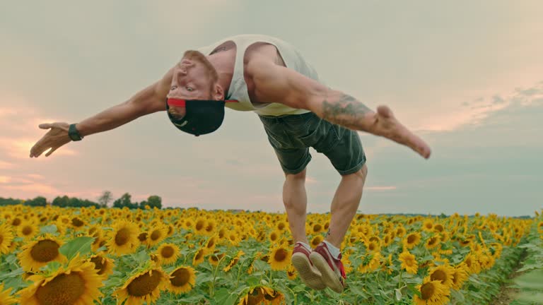 MS Acrobatic young man backflipping in field of sunflowers